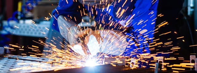 Welder welding metal in workshop with sparks